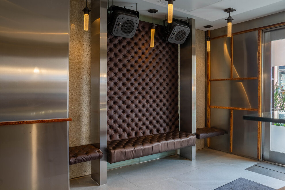 a brown leather bench with two lights from ceiling