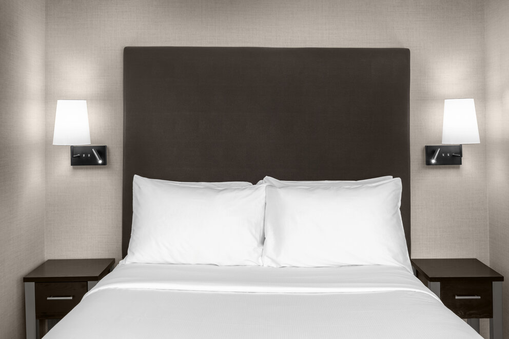 a bed with white sheets and a brown headboard