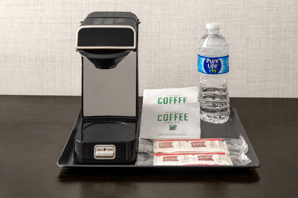 a coffee machine and a bottle of water on a tray