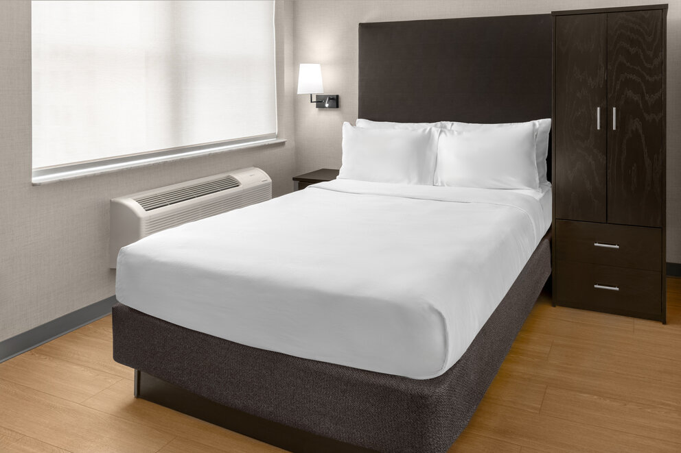a bed with white sheets and a heater