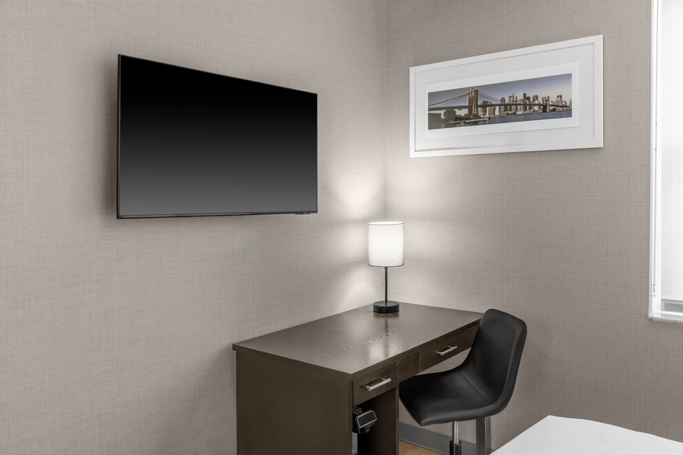 a desk with a lamp and a chair in a room with a picture on the wall