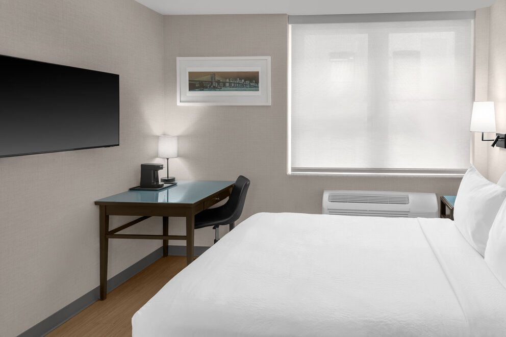 a room with a bed and a desk and a tv